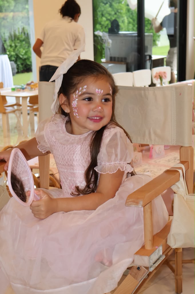 Girl with delicate flower face painting holding a mirror