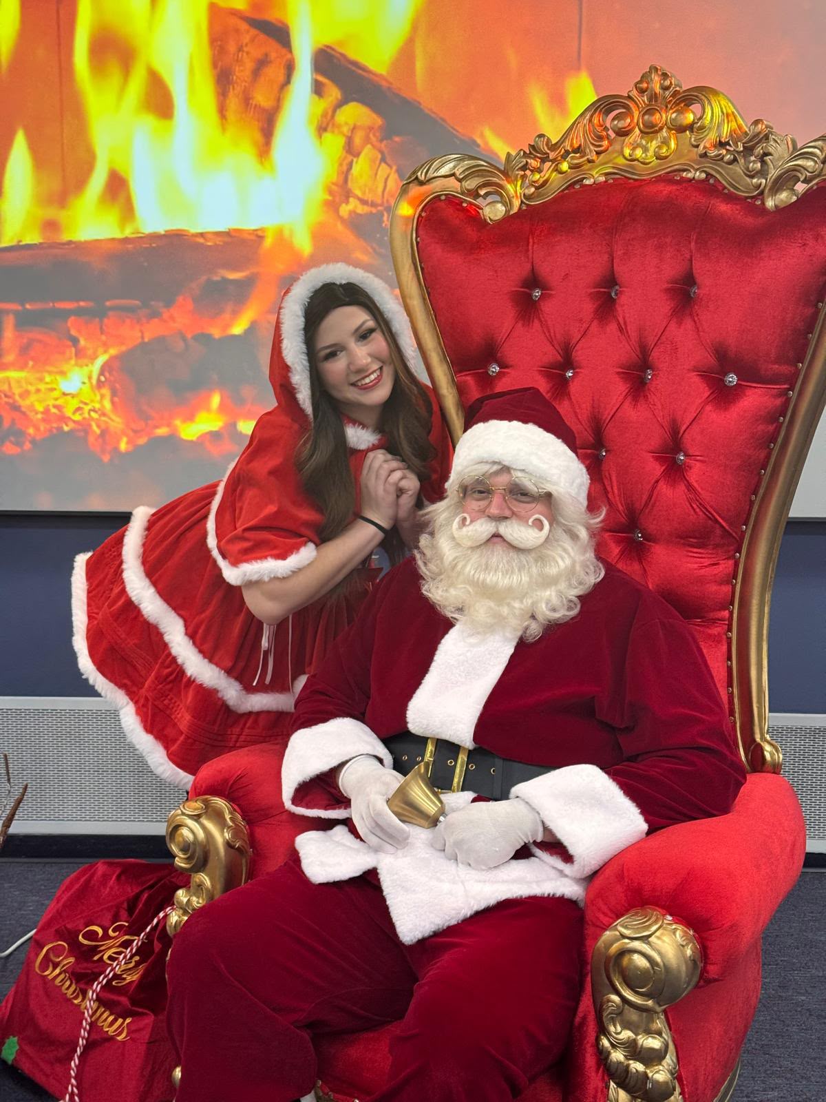 Santa Claus on his throne with a Mrs. Claus helper
