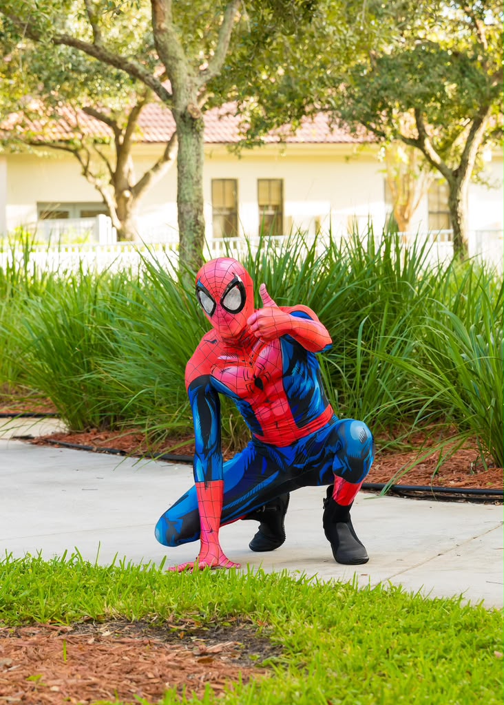 Spider hero character crouching and giving a thumbs up at a park