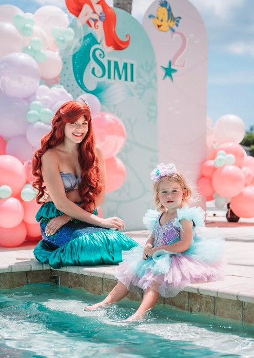 Mermaid character by the pool with a little girl
