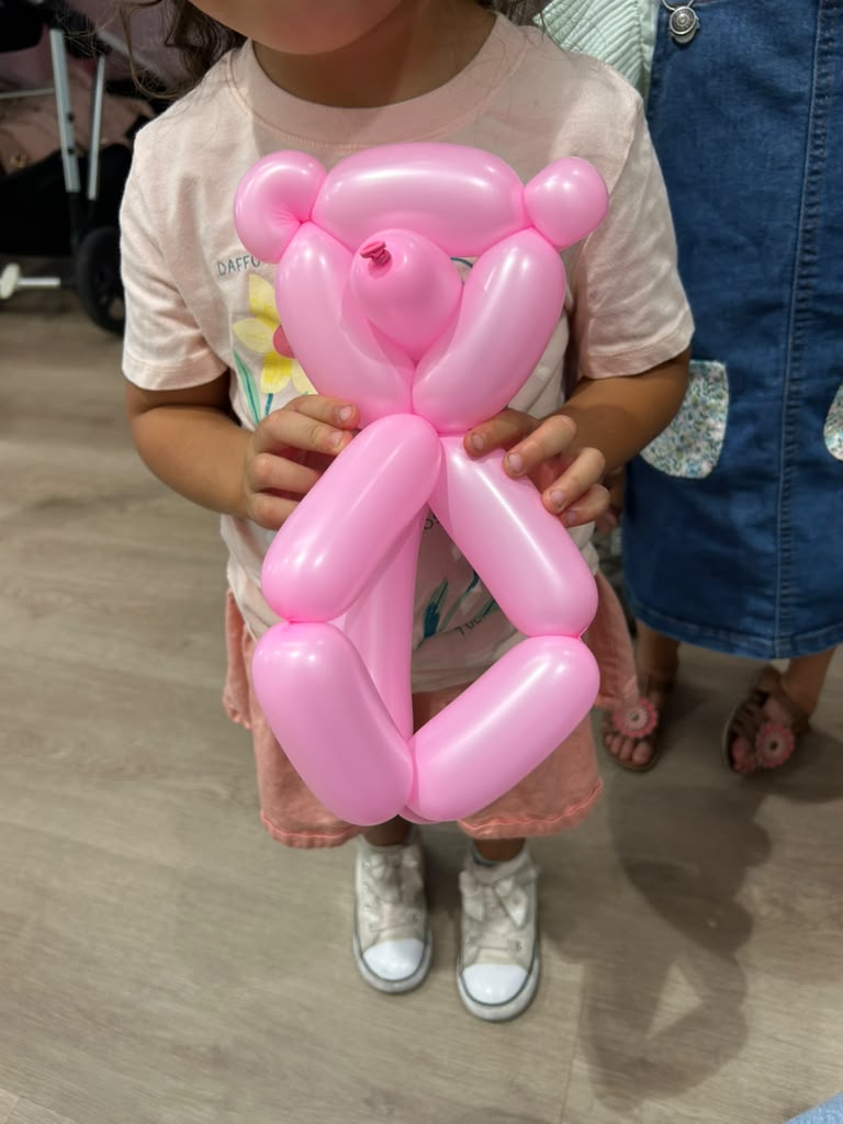Child holding a pink balloon bear at a party