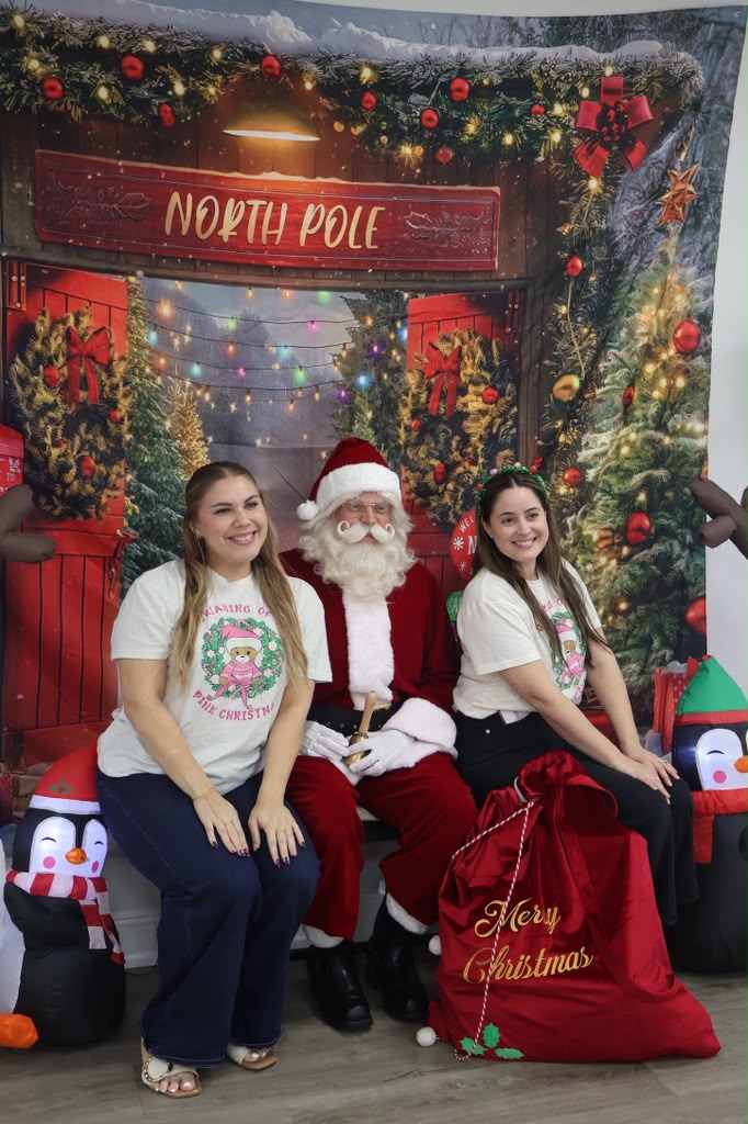 Party hosts posing with Santa at the North Pole backdrop